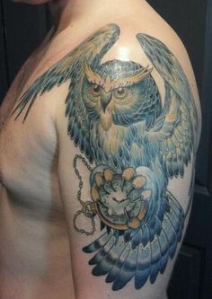 an owl tattoo on the back of a man's shoulder, with chains around it