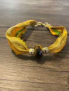 a close up of a bracelet on a wooden table with a bead around it