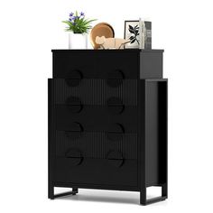 a black cabinet with drawers and pictures on it's top shelf next to a potted plant