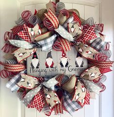 a christmas wreath hanging on the front door with an image of penguins and santa claus