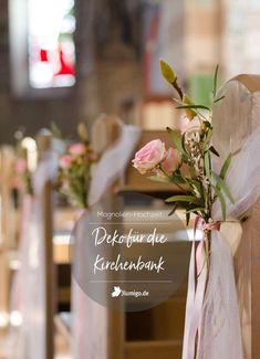 flowers are tied to the back of pews at a wedding