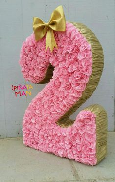 the number two is made out of pink yarn and has a bow on its head