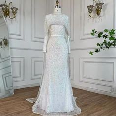 a white wedding dress on display in front of a mirror and wall sconces