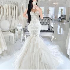 a woman taking a selfie in a wedding dress shop with her phone up to her ear