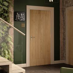 a wooden door in a green room with plants on the wall and stairs leading up to it