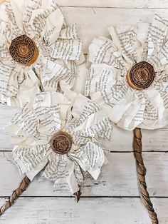 paper flowers made out of old book pages on a white wooden background with twine