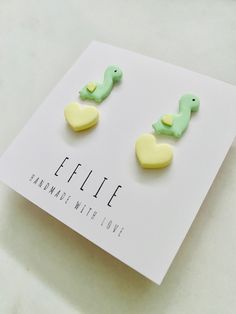 two green and yellow bird shaped earrings sitting on top of a white card with the words effiee