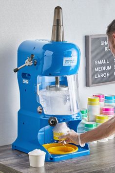 a man is washing his hands in front of an ice cream machine on a table