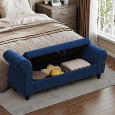 a blue couch with two pillows on top of it in front of a large bed