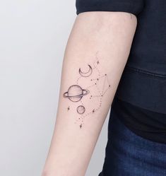 a woman's arm with two planets and stars tattoo on the left side of her arm