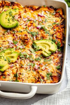 an enchilada casserole with sliced avocados and cilantro