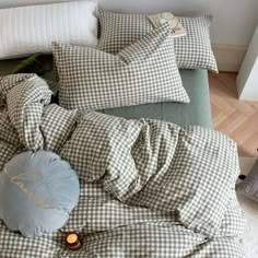 an unmade bed with pillows and blankets on top of it, next to a pillow