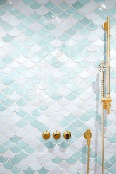 a bath room with a shower head and two faucets next to a tiled wall