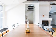 a long wooden table with chairs around it in front of a fire place and fireplace