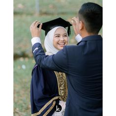 a woman in a graduation cap and gown is being congratulated by a man