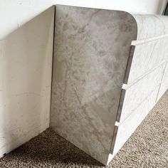 the corner of a room with a marble wall and carpeted flooring is shown