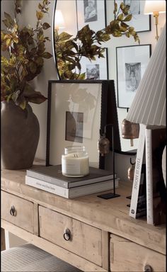 a wooden table topped with books and a lamp next to a mirror on top of it