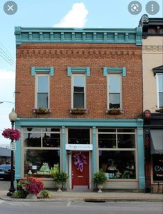 an old brick building with blue trim on the front and windows is next to a street corner