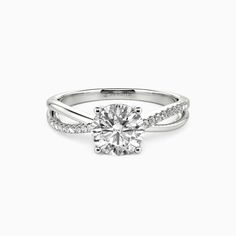 a white gold engagement ring with diamonds on the band and a round center stone in the middle