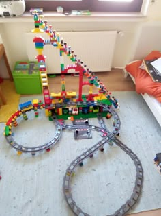 a toy train set is on the floor next to a book shelf and window in a child's bedroom