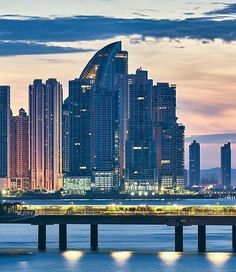 the city skyline is lit up at night, with skyscrapers in the background and lights reflecting on the water