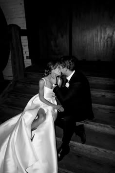 a bride and groom kissing on the stairs at their wedding reception in black and white