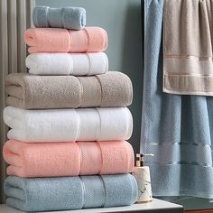 towels stacked on top of each other in front of a towel rack and window sill