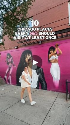 the woman is walking down the sidewalk in front of a mural