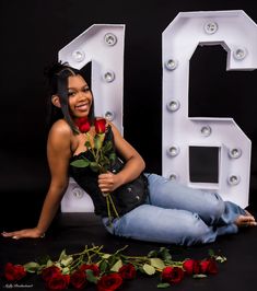 a woman sitting on the floor with roses in front of her and number twenty nine behind her