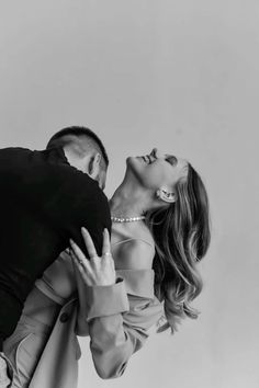 black and white photograph of a man kissing a woman's head in front of a gray background