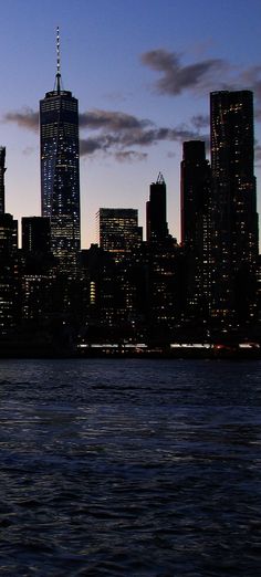 the city skyline is lit up at night, with skyscrapers in the foreground