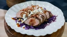 a white plate topped with meat and purple cabbage