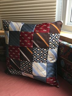 a pillow made out of ties sitting on a couch next to a window sill