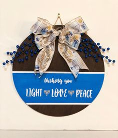 a blue and white sign with a bow hanging from it's side that says, wishing you light the love for peace