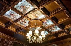 a chandelier hanging from the ceiling in a room with wood paneling and stained glass windows