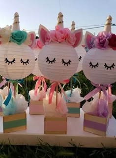 three paper lanterns with unicorn faces and eyelashes on them sitting in the grass next to each other