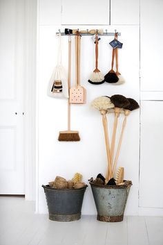 two buckets with brooms and brushes hanging on the wall