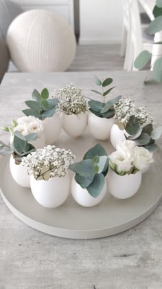 an arrangement of white eggs with flowers in them sitting on a table next to a vase