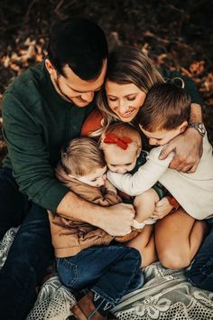 a family hugging each other while sitting on the ground