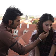 a man helping a woman put on her collar in front of the cityscape