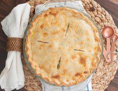 a pie sitting on top of a wooden table next to utensils and napkins