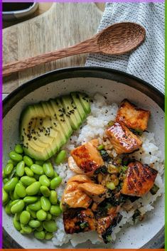 a bowl filled with rice, meat and vegetables next to a sliced avocado