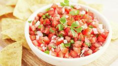 a white bowl filled with salsa surrounded by tortilla chips