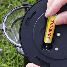 a person is holding a battery in their hand near a fire hydrant on the grass