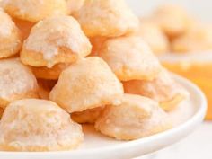 a white plate topped with lots of sugar covered doughnuts on top of a table