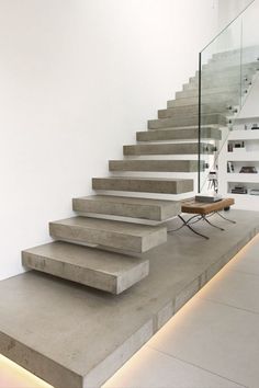 a set of concrete stairs leading up to the second floor in a modern house with white walls and floors