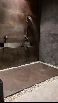 a shower head and hand shower in a bathroom with stone flooring on the walls