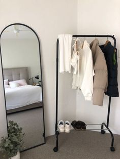 a bedroom with a mirror, clothes rack and shoes on the floor in front of it