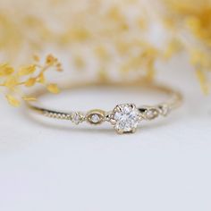 a diamond ring sitting on top of a table next to some yellow and white flowers