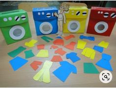 cut out pieces of paper sitting on top of a wooden table next to two toy washing machines